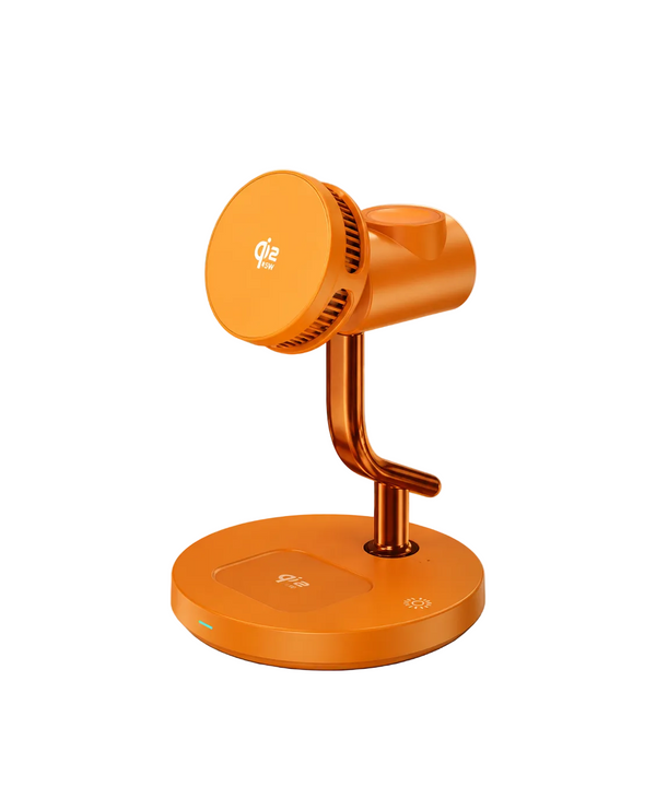 An orange portable desk fan with a curved neck and circular base, shown on a marble tabletop in a styled home office setting with a plant and books in the background.