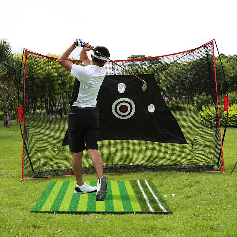 Person practicing golf swings in front of a net with a target and mat on a grassy area.