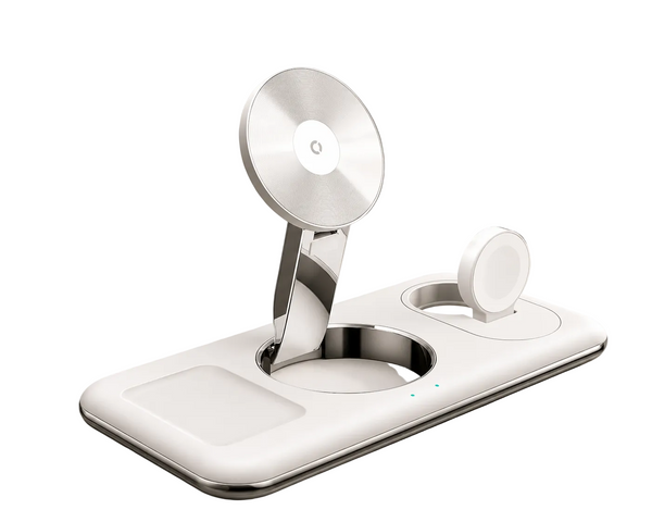 A white and silver magnetic wireless charging dock with a fold-out stand, shown on a light beige marble tabletop with a blurred potted plant in the background.