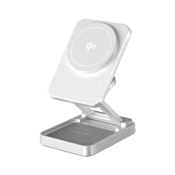 A white and silver magnetic wireless charging stand with an adjustable fold-out base, shown on a light marble tabletop in a softly lit indoor setting.